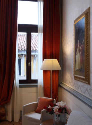 a living room with a chair and a lamp and a window at Ruzzini Palace Hotel in Venice