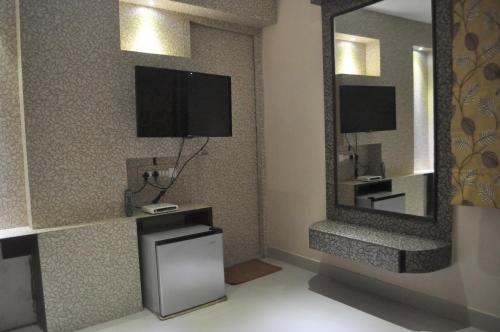 a living room with a tv and a mirror at Hotel Eastern Plaza in Kolkata