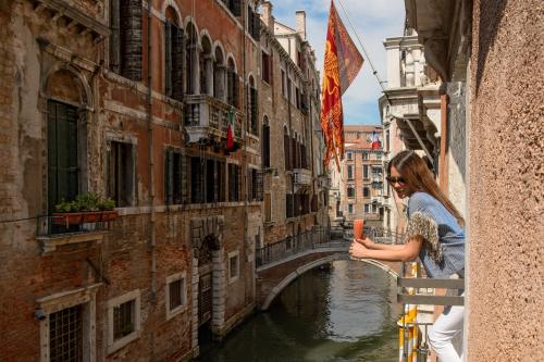 Una mujer parada en un balcón con vistas a un canal en Ruzzini Palace Hotel en Venecia