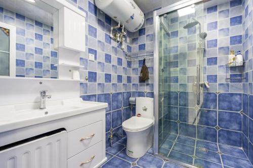 a blue tiled bathroom with a toilet and a shower at Quzhu Apartment Hotel (Wuhan Hankou Railway Station) in Wuhan