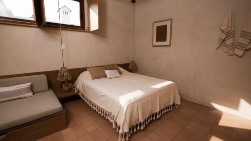 a bedroom with a bed and a couch and a window at Casa Montore by Barrio Mexico in Guadalajara