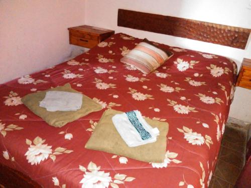 Una cama con un edredón rojo con toallas. en Cabaña Luna de Pueblo en Salta