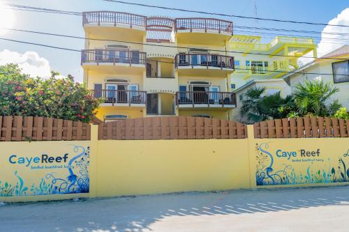 a yellow building with a fence in front of it at Caye Reef Condos in Caye Caulker