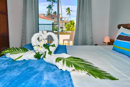 a bedroom with a bed with white towels and flowers at Las Terrazas Condo Punta Cana Beach - Los Corales Village in Punta Cana