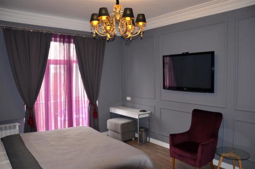 een slaapkamer met een bed, een tv en een stoel bij Kiev City Center in Kiev