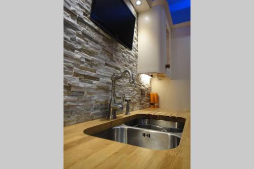 a kitchen with a sink and a stone wall at Royal Bank Flat in Oban