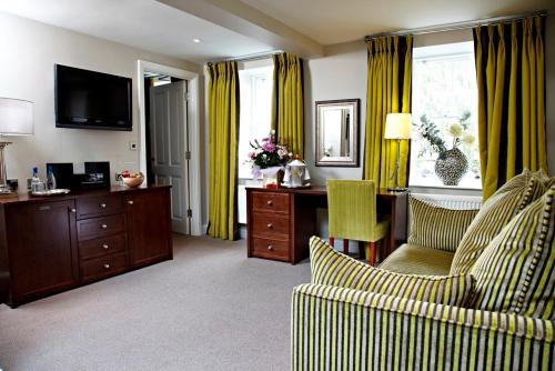 a living room with yellow curtains and a desk and a chair at Trout Hotel in Cockermouth