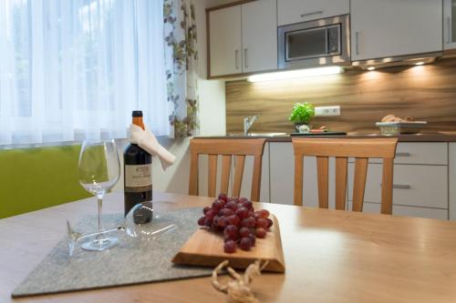 a bottle of wine and a plate of grapes on a table at Apart Garni Sesvenna in Ischgl