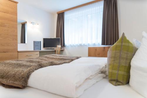 a bedroom with a white bed with a large window at Apart Garni Sesvenna in Ischgl