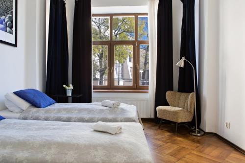 1 dormitorio con 2 camas, silla y ventana en Apartamenty Królewska, en Lublin