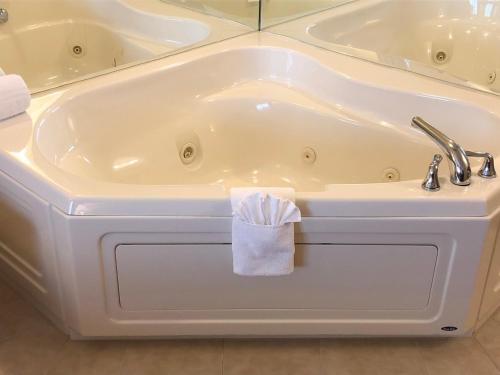 a white bath tub with a towel on it at AmericInn by Wyndham Iron Mountain in Iron Mountain