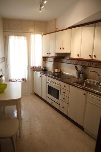 a kitchen with white cabinets and a sink and a stove at Apartamento Vega in Jaca