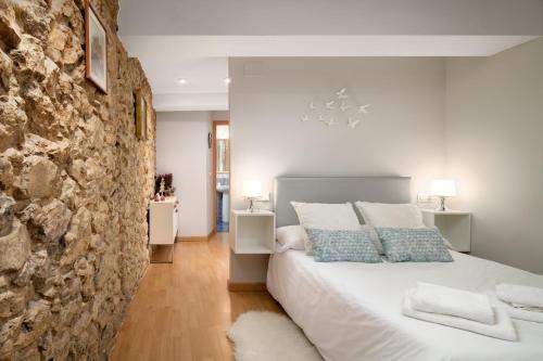 sypialnia z białym łóżkiem i kamienną ścianą w obiekcie Apartamento Supercentrico w mieście Oviedo