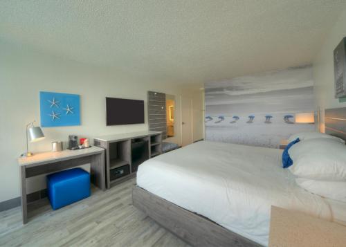 a bedroom with a bed and a desk with a television at The Island Resort at Fort Walton Beach in Fort Walton Beach