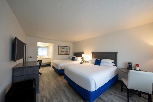 a hotel room with two beds and a flat screen tv at The Island Resort at Fort Walton Beach in Fort Walton Beach