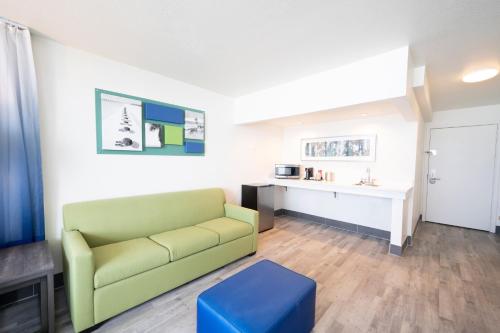 a living room with a green couch and a blue stool at The Island Resort at Fort Walton Beach in Fort Walton Beach