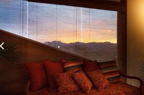 a couch with pillows in front of a window at Estrada Real Palace Hotel in Brumadinho