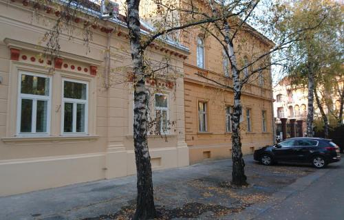 due alberi di fronte a un palazzo con un'auto di Konzul a Osijek