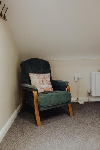 a green chair with a pillow in a room at Betty's Loft in Lisburn