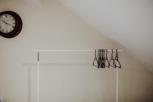 a clock on a wall next to a shelf with glasses at Betty's Loft in Lisburn