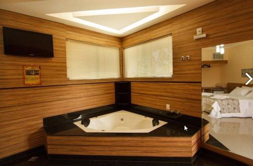 a large bath tub in a room with a tv at Estrada Real Palace Hotel in Brumadinho