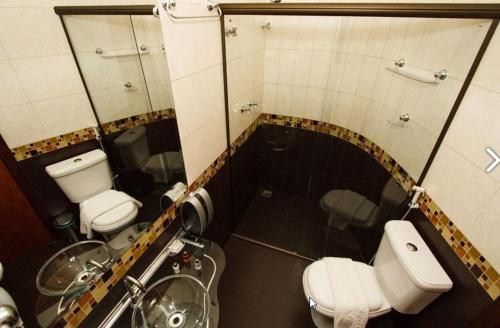 a bathroom with two toilets and a sink and mirror at Estrada Real Palace Hotel in Brumadinho