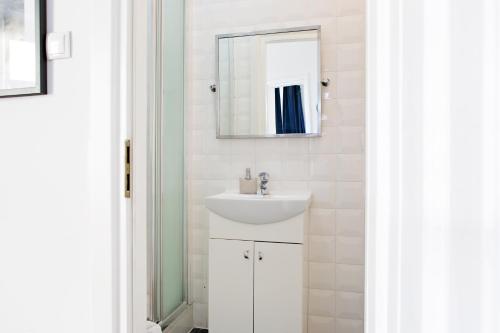 a white bathroom with a sink and a mirror at Apartamenty Królewska in Lublin