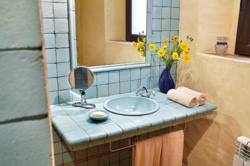 a bathroom sink with a mirror and a vase of flowers at Mas can Salvi in Parlavà