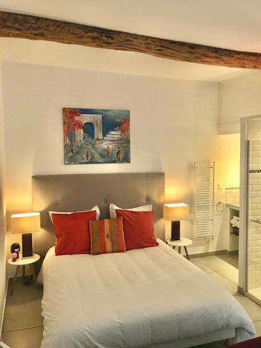 une chambre avec un grand lit blanc avec des oreillers rouges dans l'établissement La Maison du Courtil, Figue-Miel, à Moustiers-Sainte-Marie