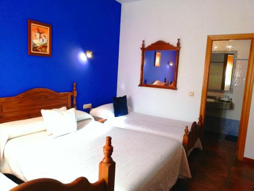a blue bedroom with two beds and a mirror at Hostal Restaurante Ego's in Campo de Criptana