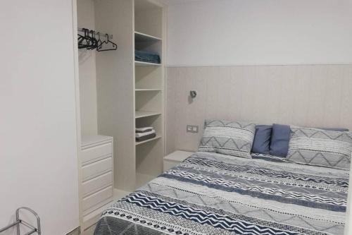 1 dormitorio con 1 cama con almohadas azules y grises en Apartamento Acuario en Arinaga