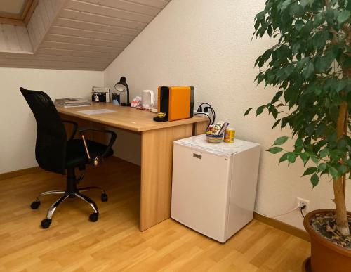 ein Büro mit einem Schreibtisch mit einem Stuhl und einem Kühlschrank in der Unterkunft Queen Guest Room in Mont-sur-Rolle