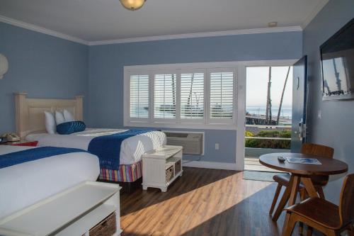 a bedroom with two beds and a table and a window at Beach Street Inn and Suites in Santa Cruz