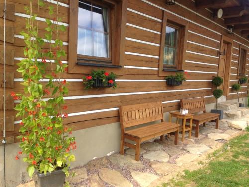 two benches sitting in front of a house with flowers at Apartmán U Setra in Pec pod Sněžkou