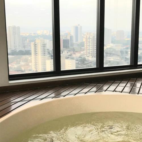 a bath tub in a room with windows at Airport Business Flat Guarulhos - São Paulo in Guarulhos