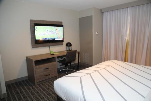 a hotel room with a bed and a desk with a television at La Quinta by Wyndham Montgomery in Montgomery