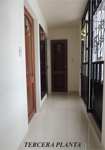 a hallway with two doors and white flooring in a house at Sueños Vividos Hospedaje in Sogamoso