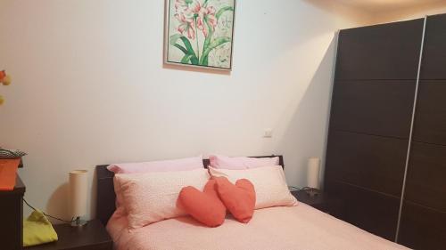1 dormitorio con 1 cama con almohadas rosas y blancas en B&B Kristina en Quinto Vicentino