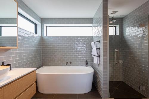 a bathroom with a white tub and gray tiles at Whakarire in Queenstown