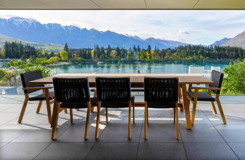 a wooden table and chairs with a view of a lake at Whakarire by Sotheby's Luxury Rental Homes in Queenstown