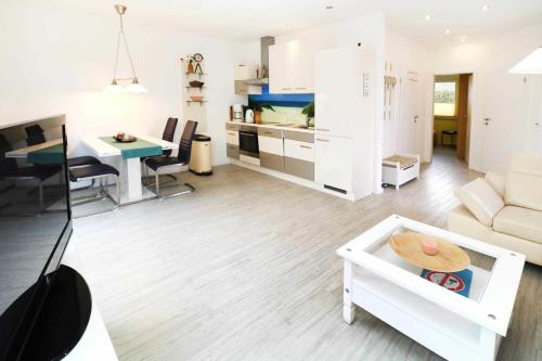 a white living room with a couch and a table at Ferienwohnung Wiesenglueck_EHRL in Ostseebad Karlshagen