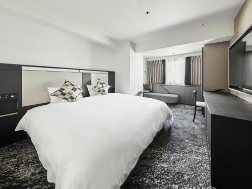a hotel room with a large white bed and a television at Cross Hotel Osaka in Osaka