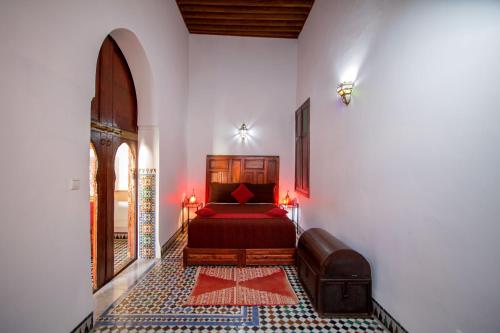 1 dormitorio con 1 cama en una pared blanca en Riad Zitouna, en Fez