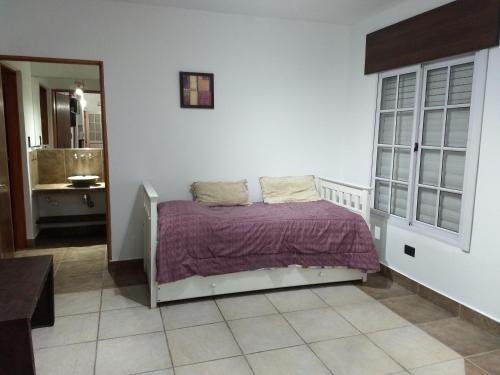 1 dormitorio con 1 cama con sábanas moradas y baño en Depto, planta baja en Salta