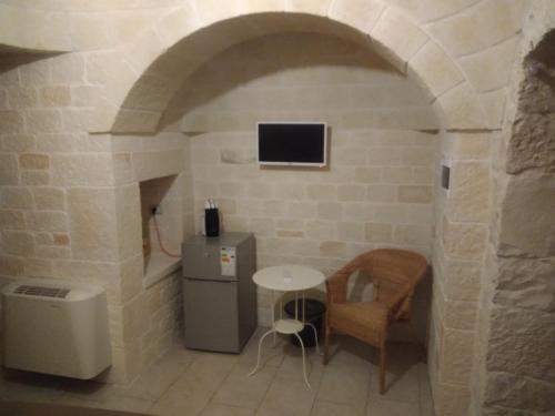 a room with a table and a tv in a stone wall at RITORNO AD ITACA in Locorotondo