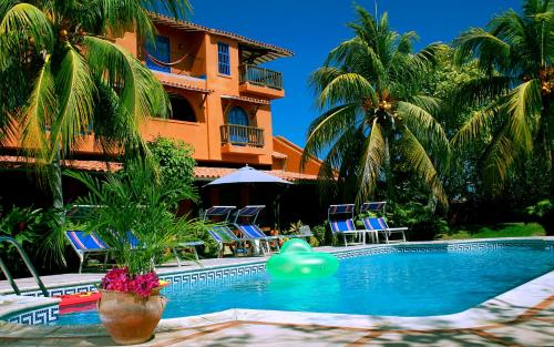 a swimming pool in front of a building with palm trees at Hotel Costa Linda Beach in La Loma