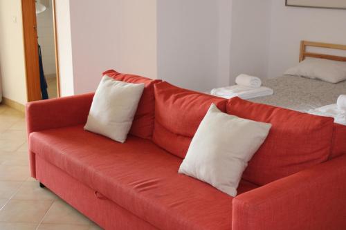 un canapé rouge avec deux coussins blancs dessus dans l'établissement Magnoliamar 409, à Lagos