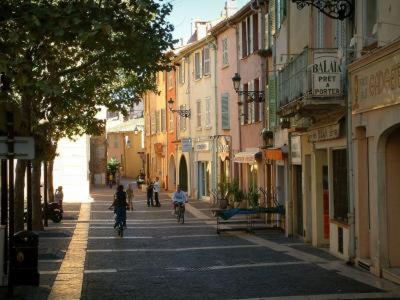 dos personas montando bicicletas por una calle de la ciudad con edificios en Charmant Studio au cœur historique de Fréjus, en Fréjus