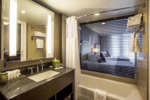 a bathroom with a sink and a mirror and a bed at Pinnacle Hotel at the Pier in North Vancouver