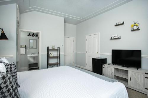 a white bedroom with a bed and a flat screen tv at Hounds Tooth Inn in Oakhurst